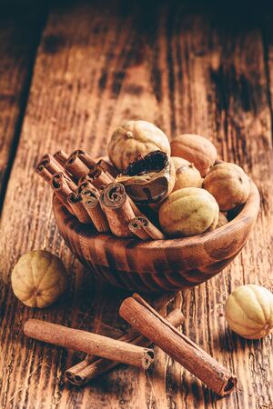 Cinnamon sticks and dried limes in wooden bowl on rustic tableの写真素材