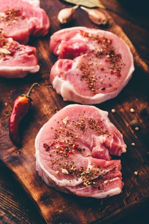 Pork loin steak with different spices on chopping boardの写真素材