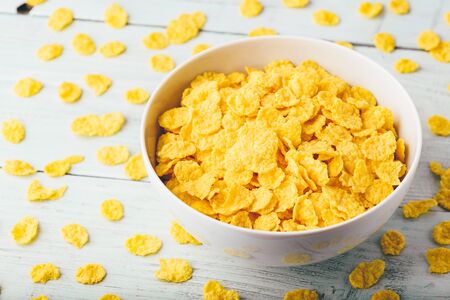 White bowl of corn flakes on a wooden surfaceの写真素材