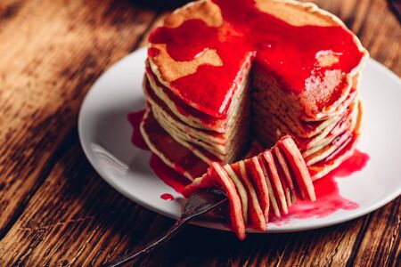 Stack of pancakes with berry fruit marmalade on plate over wooden surfaceの写真素材