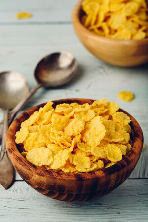 Rustic bowls of cornflakes with spoons on light wooden surfaceの写真素材