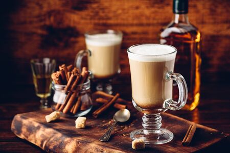 Coffee with Irish whiskey and whipped cream in glass on rustic wooden surfaceの写真素材