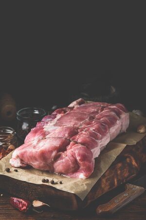 Raw pork loin joint on cutting board with different spicesの写真素材