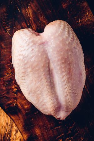 Raw chicken breast on rustic chopping board