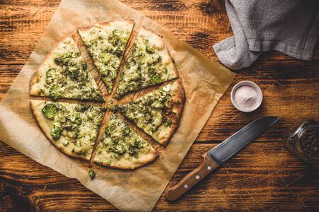 Sliced Italian pizza with broccoli, pesto sauce, herbs and parmesan on baking paper. View from aboveの写真素材