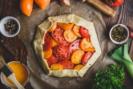 Uncooked tomato galette on baking paper. View from aboveの写真素材
