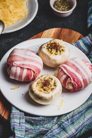 Preparing of bacon-wrapped button mushrooms stuffed with grated cheddar cheese and spicesの写真素材