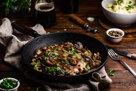 Fried pork neck steak with different mushrooms and mashed potatoesの写真素材