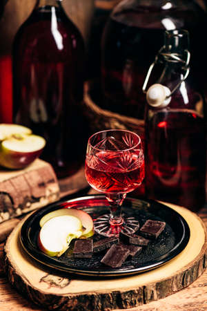 Homemade red currant nalivka and chocolate with sliced apple on metal trayの写真素材