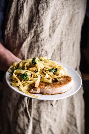 Pork chop steak and pasta with capers and lemon zestの写真素材