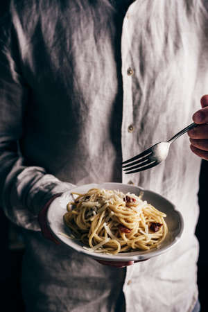 White plate with classic carbonara pasta in male handsの写真素材