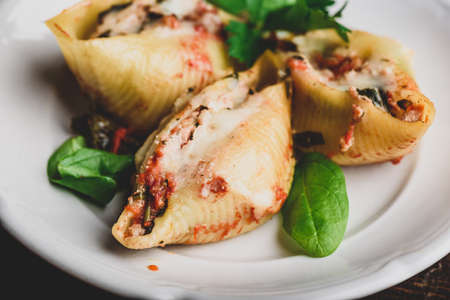 Baked jumbo shells pasta stuffed with ground beef, spinach and cheese on white plateの写真素材