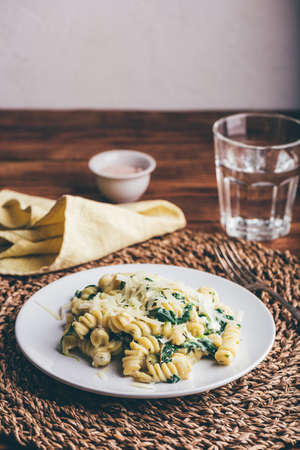 Fusilli Pasta with Spinach and Ricotta Garnished with Grated Parmesan Cheese on White Plateの写真素材