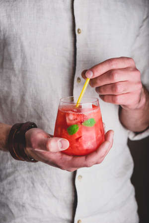Glass of watermelon cocktail with gin and soda in handsの写真素材