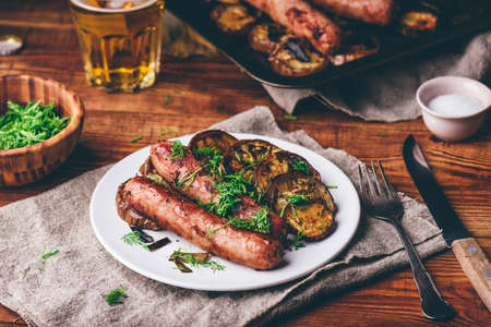 Pork Sausages Baked with Eggplant and Herbs on White Plate Garnished with Dillの写真素材