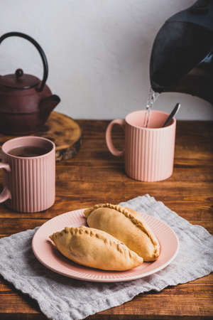 Two Homemade Cabbage Mini Pies on Plate and Mugs with Teaの写真素材