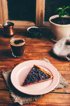 Slice of Fresh Baked Serviceberry Open Pie on Plate and Glass of Turkish Coffee on Wooden Tableの写真素材