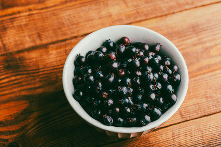 Ripe Purple Berries of Shadbush in Vintage Bowl on Wooden Table. high angle viewの写真素材