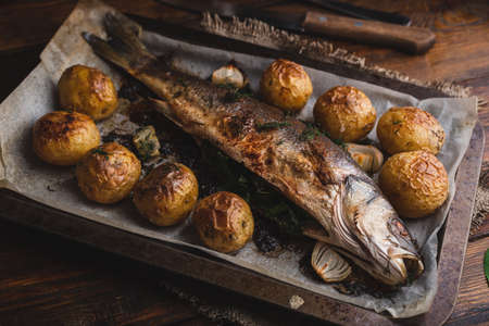 Freshly Baked Fish Stuffed with Sorrel and New Potatoes on Baking Sheetの写真素材