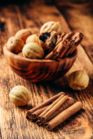Cinnamon sticks and dried limes in wooden bowl on rustic tableの写真素材