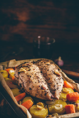 Seasoned chicken breast baked in oven with vegetables on baking sheetの写真素材