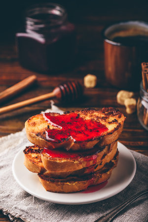Stack of French toasts with berry syrup on white plateの写真素材