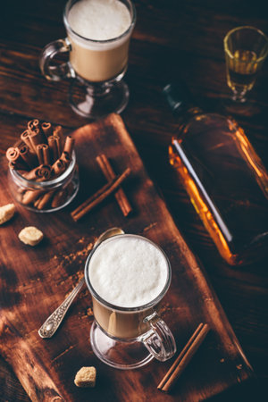 Coffee with Irish whiskey and whipped cream in glass on rustic wooden surfaceの写真素材