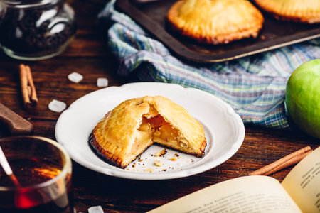 Homemade apple mini pie on white plate with cup of black teaの写真素材
