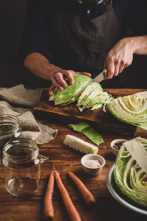 Man is Shredding White Cabbage with Knife for Fermentingの写真素材