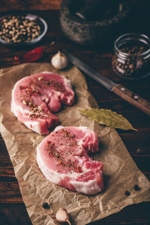 Pork loin steaks with ground spices on baking paperの写真素材