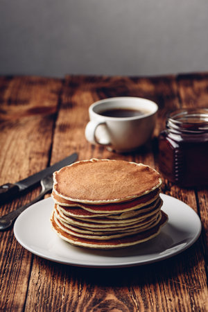 Stack of pancakes on white plate over wooden surfaceの写真素材