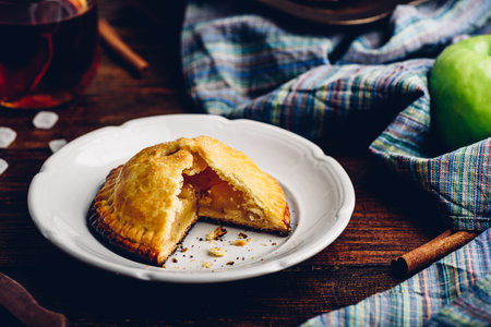 Homemade apple mini pie on white plate with cup of black teaの写真素材
