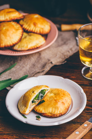 Oven Baked Hand Pies Filled with Chives and Mushrooms on White Plate and Glass of Wineの写真素材