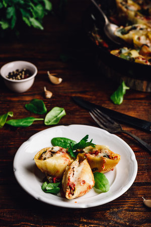 Baked jumbo shells pasta stuffed with ground beef, spinach and cheese on white plateの写真素材