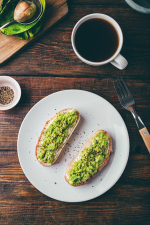 Avocado toasts and cup of coffee on rustic table. View from aboveの写真素材