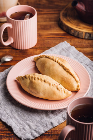 Two Fresh Baked Cabbage Hand Pies on Plate for Breakfastの写真素材