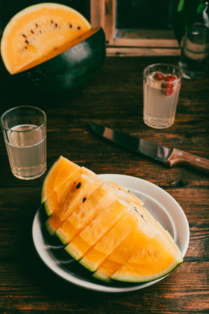 Yellow Watermelon Cut in Slices on Rustic Tableの写真素材