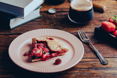 A Piece of Fresh Baked Strawberry Sorrel Open Pie on Plate and Glass of Porterの写真素材
