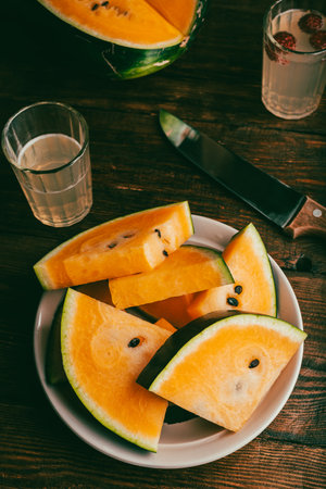 Delicious Yellow Watermelon Cut in Slices on a Wooden Tableの写真素材