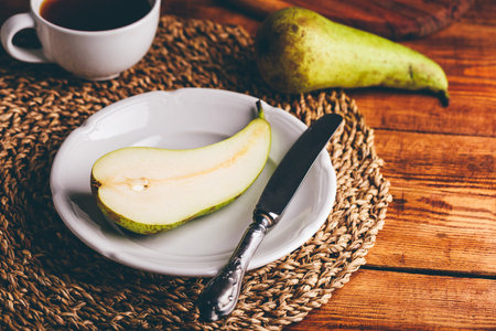 Halved Green Pear on White Plate with Knifeの写真素材