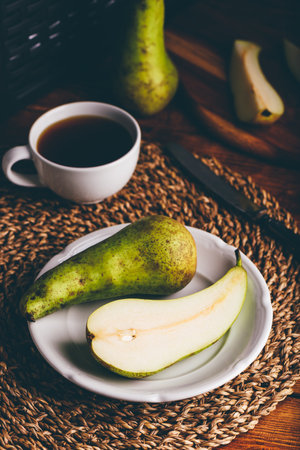 Halved Conference Pear on White Plate and Cup of Coffeeの写真素材