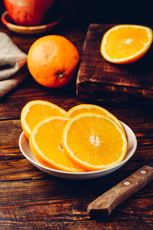 Slices of orange on white plate in rustic settingの写真素材