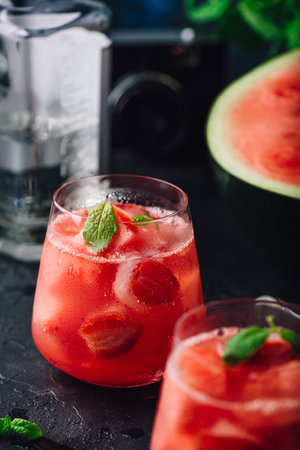 Glasses of watermelon and strawberry cocktail with mint garnish on dark concrete backgroundの写真素材