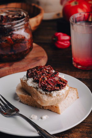 Toast with cream cheese and sun-dried tomatoes on white plateの写真素材