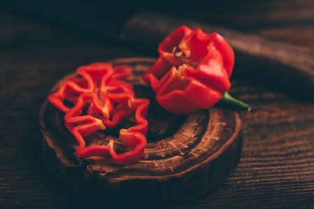 Sliced Orange Habanero Pepper on a Dark Wooden Surfaceの写真素材