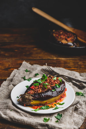Baked eggplant stuffed with ground beef, tomatoes and spices on white plate. Traditional dish Karniyarik of Turkish cuisineの写真素材