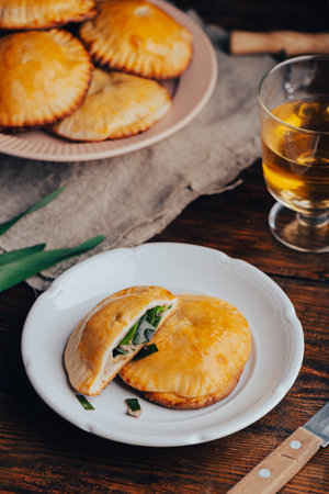 Oven Baked Pastries Filled with Blue Chives and Mushrooms on White Plate and Glass of Wineの写真素材