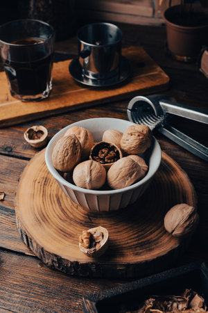 Vintage bowl full of walnuts and nutcracker on rustic tableの写真素材
