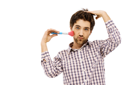 Close-up portrait of handsome romantic young blue-eyed dark-haired man with brush wearing casual plaid shirt. Self make up. Isolated.の写真素材