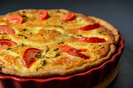 Close-up cropped photo of classic quiche lorraine pie with tomatoes, over grey textural surfaceの写真素材
